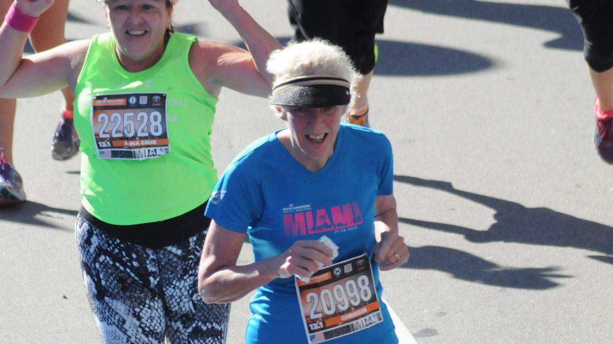Joan Chrissos, in blue shirt, crosses the finish line with her running partner, Alina Cruz, in the green shirt, at the Miami Marathon and Half Marathon, Jan. 25, 2015. It was their first half marathon, 13.1 miles. They train with TeamFootWorks in South Miami and will run together in Sunday’s Miami Half Marathon.