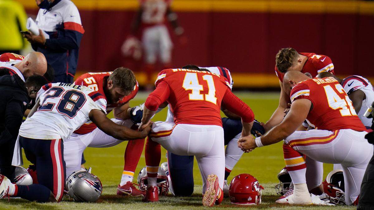 New England Patriots running back James White (28), Kansas City Chiefs linebacker Ben Niemann (56), James Winchester (41) and Kansas City Chiefs running back Anthony Sherman (42) hold hands to pray after an NFL football game, Monday, Oct. 5, 2020, in Kansas City. The Chiefs won 26-10.