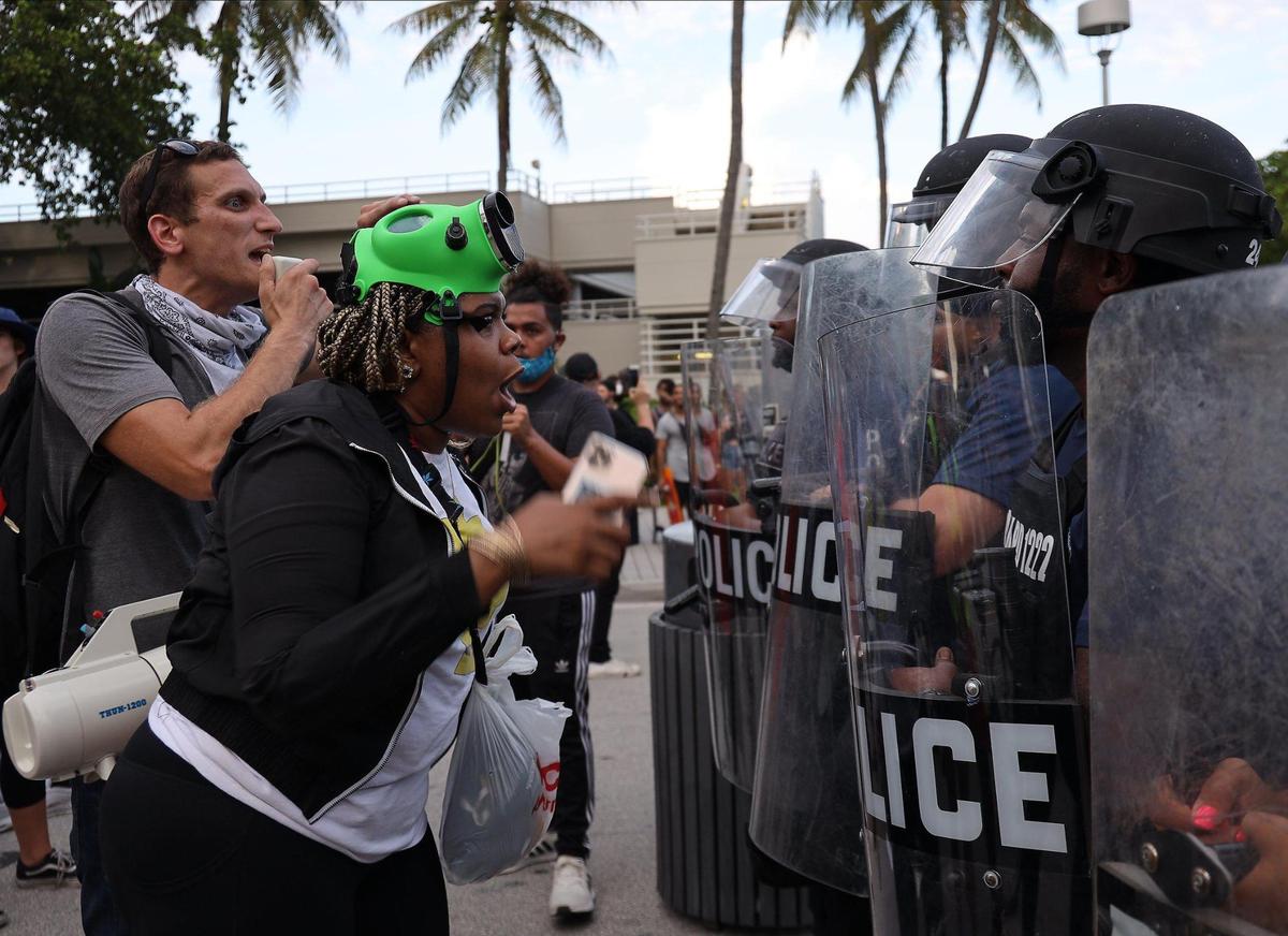Los manifestantes se enfrentan a una línea de policía después de que varios fueron arrestados cuando el pequeño grupo desfiguraba una estatua de bronce de Colón y una escultura de Ponce de León en Miami el miércoles 10 de junio de 2020.