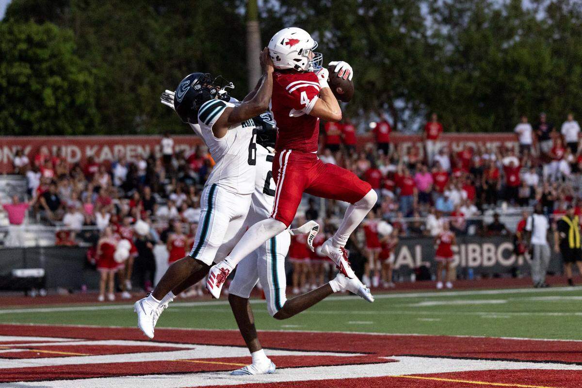 Cardinal Gibbons wide receiver Luke Cichoski (4) catches the ball for a touchdown over Archbishop McCarthy corner backs Jacarri Watson (6) and Justin Antenor (24) during a football game at Cardinal Gibbons High School on Thursday, August 21, 2025, in Miami, Fla.