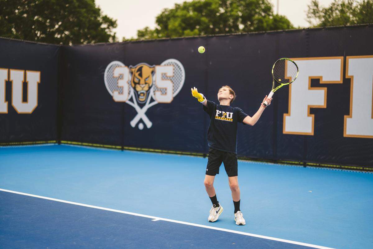 Hayden Thomas, 11, throws a tennis ball with his 3D-printed prosthetic while playing tennis at Florida International University’s main campus on Southwest Eighth Street.
