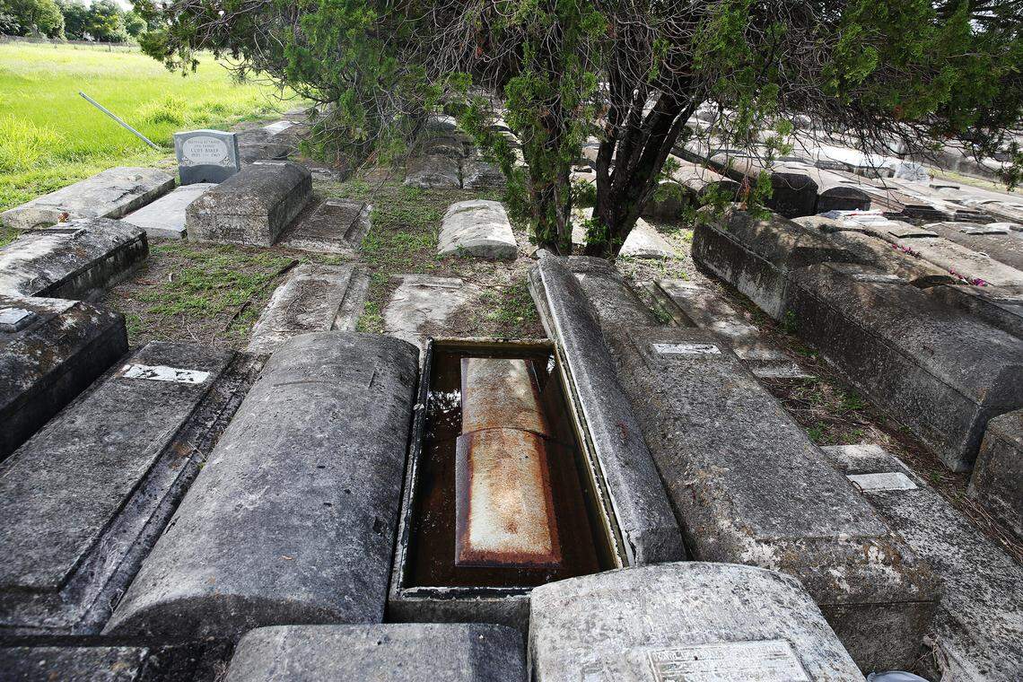 A casket is immersed in rain water after its concrete lid was pried open by vandals recently at Evergreen Memorial Park Cemetery in Brownsville.