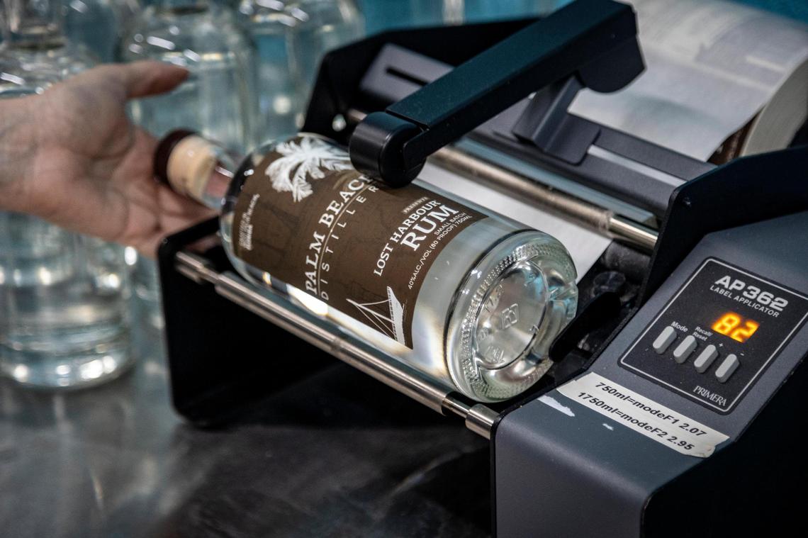 Summer Piep attaches a label to a bottle of rum in May at Palm Beach Distillery, 1142 Old Okeechobee Road in West Palm Beach, Florida.