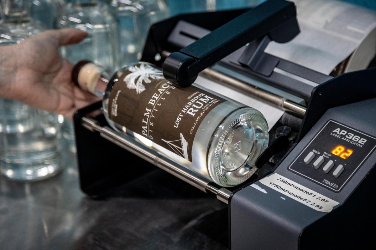 Summer Piep attaches a label to a bottle of rum in May at Palm Beach Distillery, 1142 Old Okeechobee Road in West Palm Beach, Florida.
