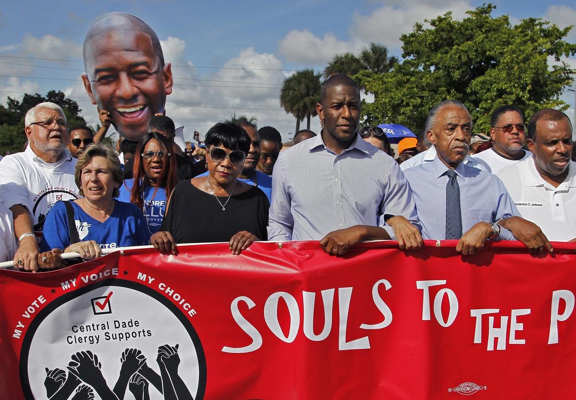 Andrew Gillum, Tallahassee mayor and Democratic nominee for Florida governor, center, marches to the Caleb Center arm-locked with Al Sharpton as part of “Souls to the Polls” on Sunday, Nov. 4, 2018.