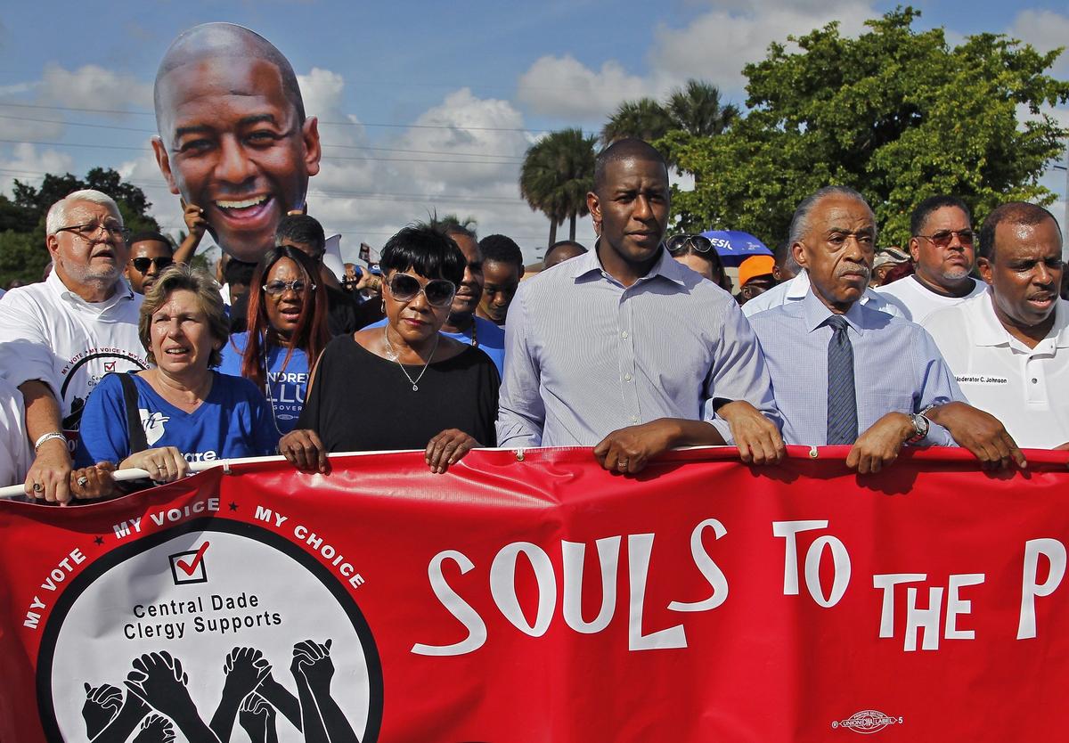 Andrew Gillum, Tallahassee mayor and Democratic nominee for Florida governor, center, marches to the Caleb Center in Brownsville arm-locked with Al Sharpton as part of “Souls to the Polls” on Sunday, Nov. 4, 2018.
