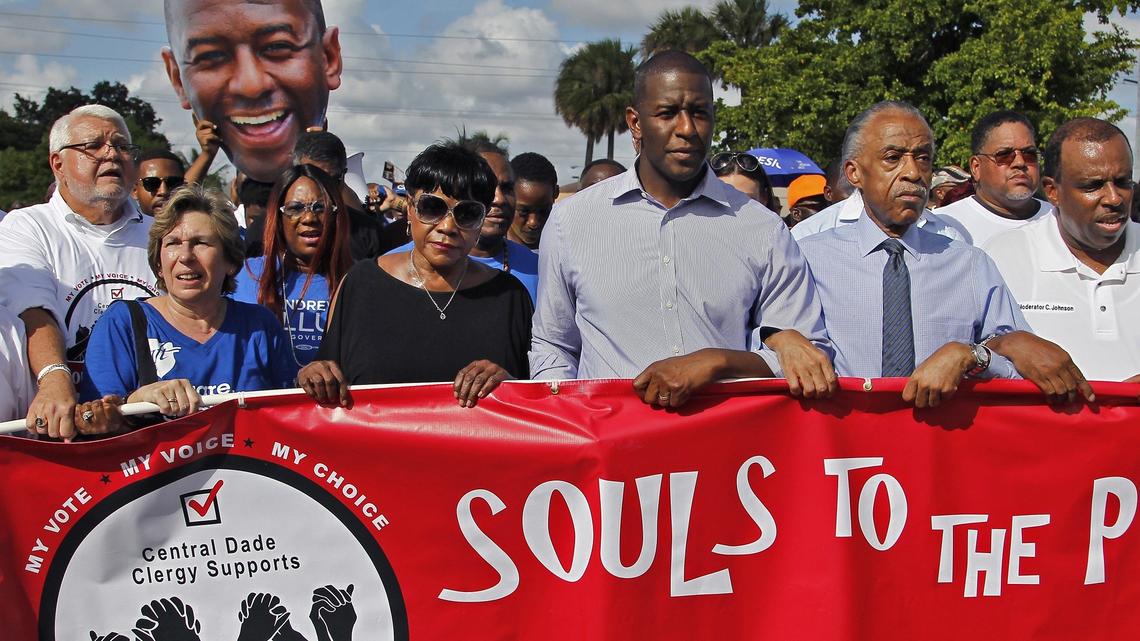Andrew Gillum, Tallahassee mayor and Democratic nominee for Florida governor, center, marches to the Caleb Center arm-locked with Al Sharpton as part of “Souls to the Polls” on Sunday, Nov. 4, 2018.