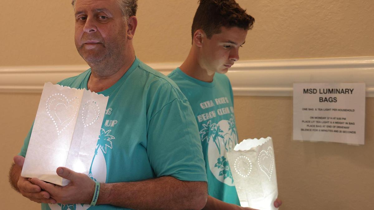 After postponing the annual beach cleanup in honor of his daughter Gina Rose Montalto, Tony Montalto and his son Anthony Montalto III, right, are photographed with luminaries to raise awareness and charitable giving for the foundation that bears his daughter’s name on Sunday, Feb. 13, 2022.