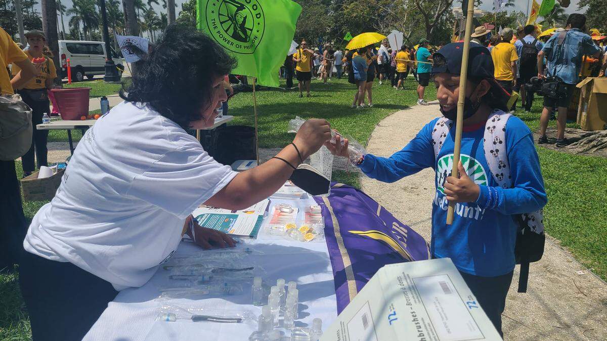 A volunteer provides health information at an outdoor health event. Community health workers often meet community members at places they frequent.
