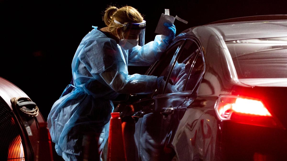 A medical professional administers a nasal swab to a person at the Tropical Park COVID-19 testing site in west Miami-Dade.