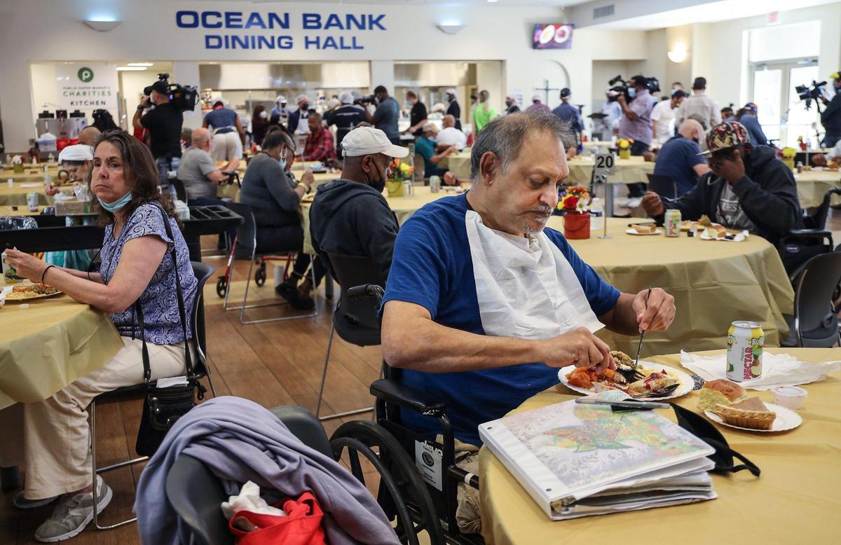 Client Andy Ali, 61, right, enjoys a warm meal. In celebration of the 60th annual Thanksgiving Day feast Camillus House limited the number of volunteers to 40 and requiring pre-event testing for those who have signed up to serve 300-plus people who live there, plus another 150 unsheltered homeless men and women in an open-air tent at the Norwegian Cruise Line Campus of Camillus House on Thanksgiving Day, November 26, 2020.