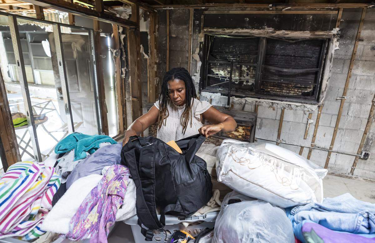 Pauline Dufresne, 39, looks through some of her personal belongings in what used to be her bedroom on Wednesday, Nov. 5, 2025, in Miami, Fla. Dufresne, a Haitian TPS holder, lost her home to a fire in July and, without insurance, has been left without power, running water or a place to live. She and her four children are temporarily staying with a nearby neighbor.
