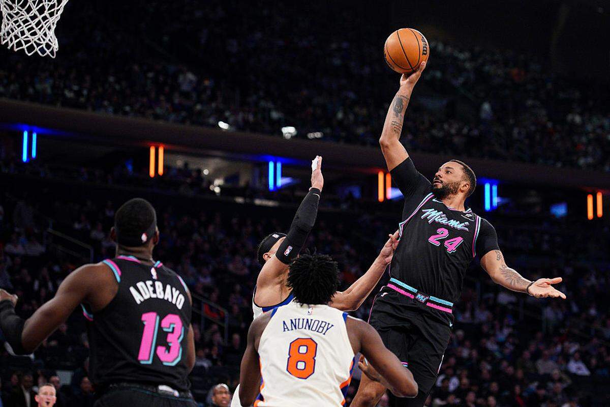 Norman Powell #24 of the Miami Heat shoots over Josh Hart #3 and OG Anunoby #8 of the New York Knicks in the second half at Madison Square Garden on December 21, 2025 in New York City.