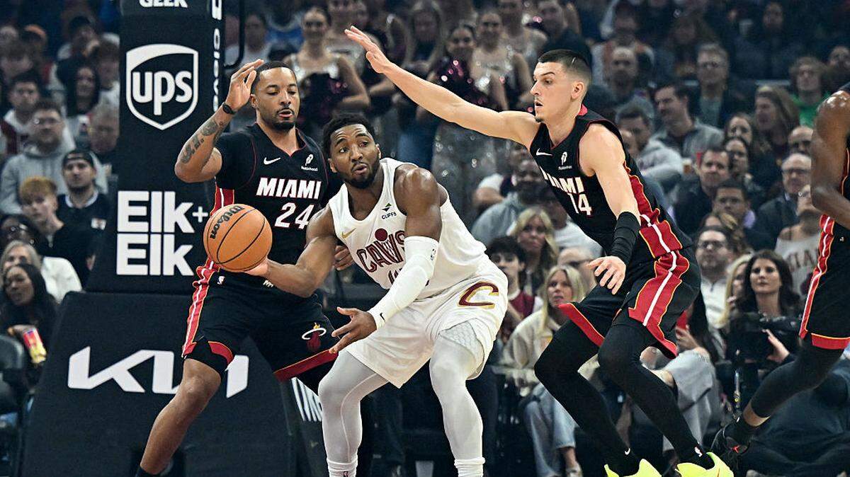 Donovan Mitchell #45 of the Cleveland Cavaliers passes the ball as he is pressured by Norman Powell #24 and Tyler Herro #14 of the Miami Heat during the first half at Rocket Arena on March 25, 2026 in Cleveland, Ohio.