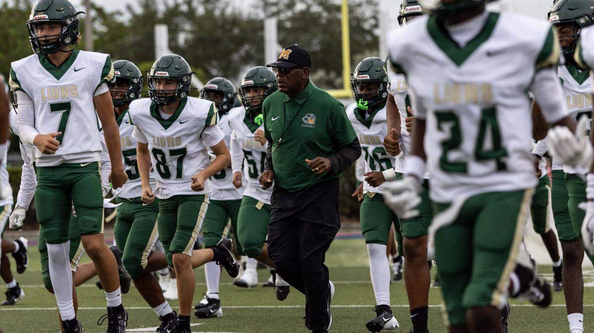 Mater Head Coach Tim "Ice" Harris jogs onto the field with his team before the first half of a high school football game at Doral Academy on Thursday, August 28, 2025, in Doral, Fla.