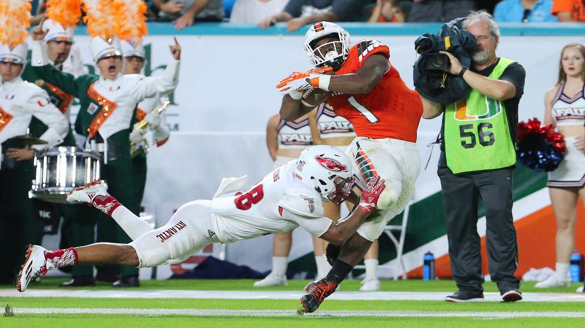 University of Miami Hurricanes running back Mark Walton runs against FAU Owls safety Jalen Younin the second quarter of an NCAA college football game, Saturday Sept. 10, 2016, in Miami Gardens.
