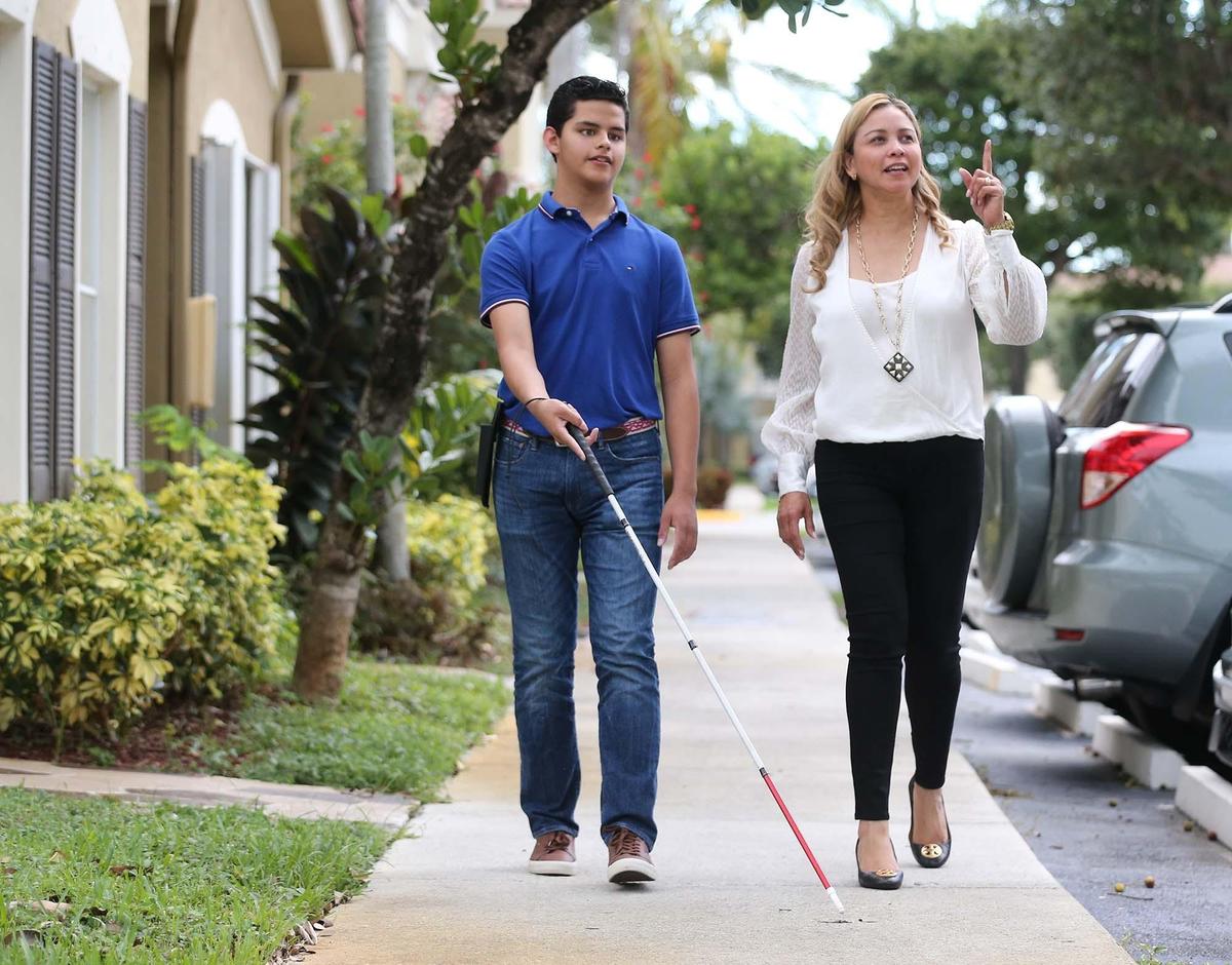 Silvio Plata and his mother, Ileana, walk in their West Miami-Dade neighborhood on June 12. Silvio, 15, will compete in the 2019 Braille Challenge National Finals in California. ‘I feel very proud that he is such a good Braille reader,’ his mother said.