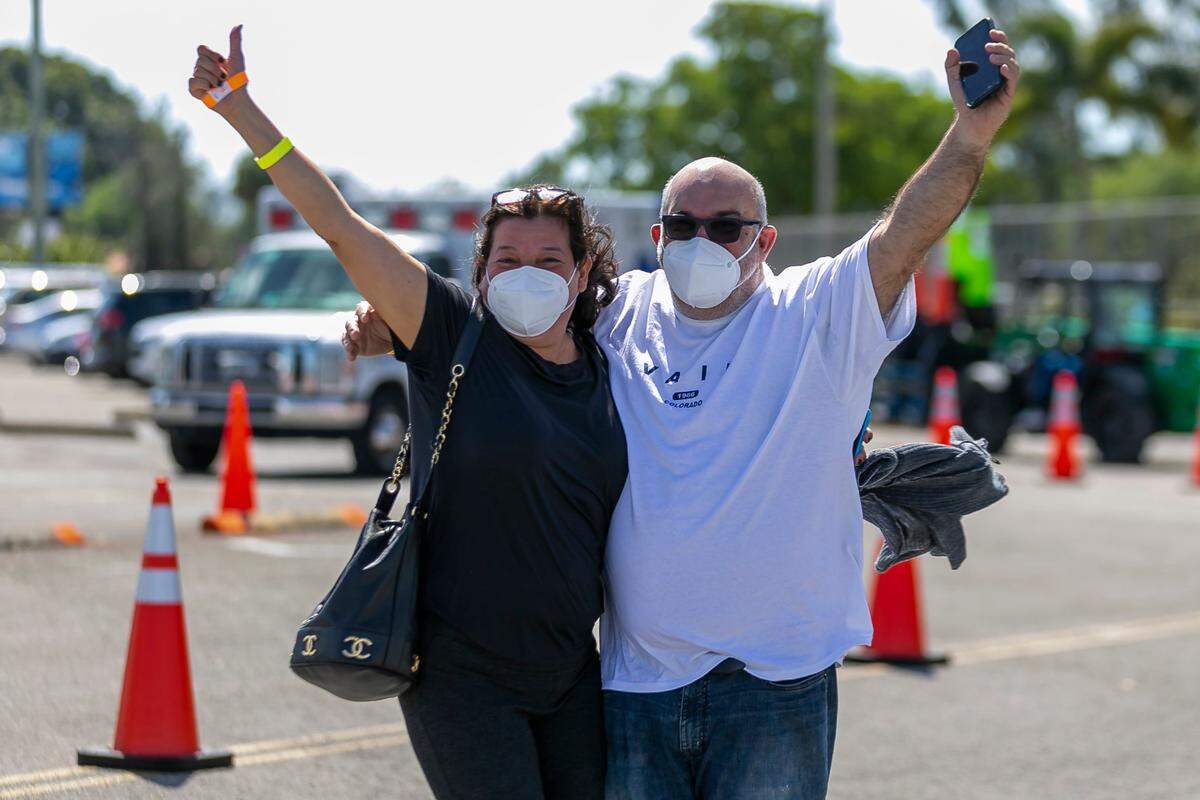Rosa Márquez, de 56 años, y su esposo, Rafael Márquez, de 59, celebran tras vacunarse contra el COVID-19 en el centro de inoculación Miami Dade College North, en Miami, el 7 de marzo de 2021.