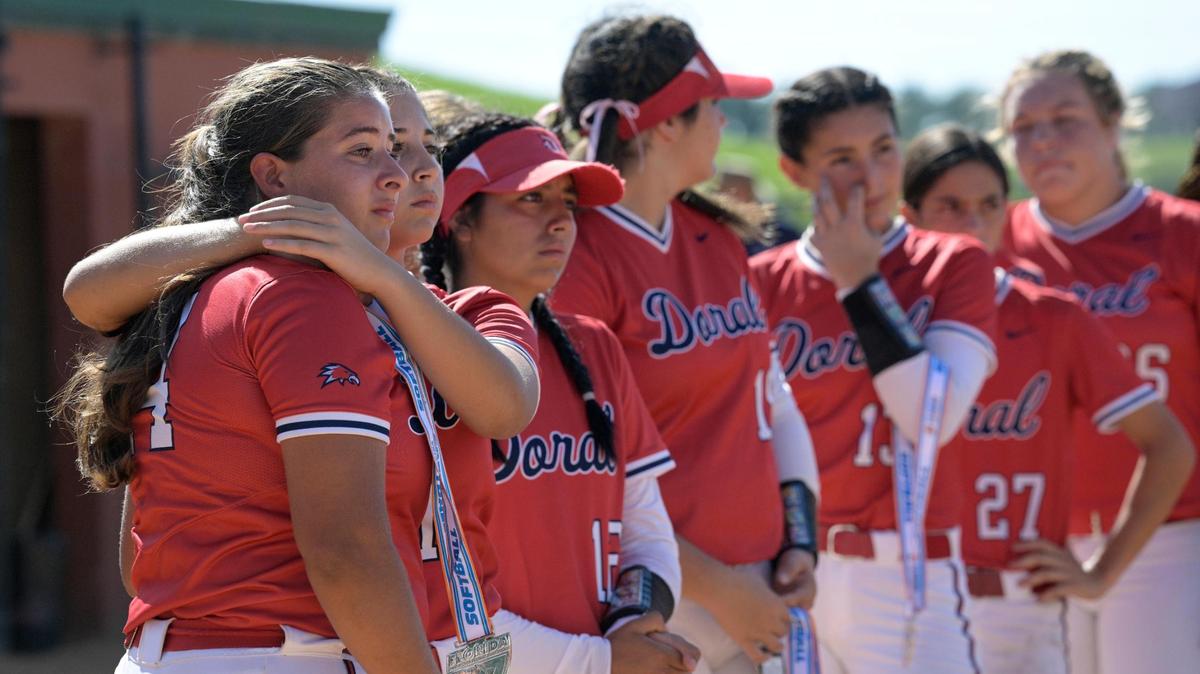 Doral Academy’s Leyani Viruet, left, is comforted by Lauren Ali as they watch the Melbourne players receive their medals after an FHSAA State Championship Softball Game, Saturday, May 28, 2022, in Clermont, Fla. (Phelan M. Ebenhack for the Miami Herald)