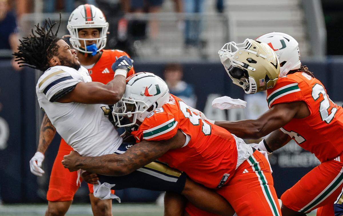 Georgia Tech Yellow Jackets running back Trey Cooley (3) loses his helmet after a hit by Miami Hurricanes defensive lineman Ahmad Moten Sr. (99) in the second half during an NCAA game at Bobby Dodd Stadium at Hyundai Field in Atlanta, Georgia on Saturday, November 9, 2024. 