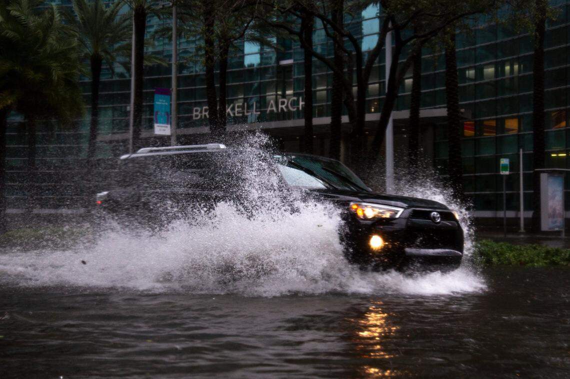 A black Toyota SUV drives through a flooded section of Brickell Avenue due to Tropical Storm Eta in Miami, Florida, Monday, Nov. 9, 2020.