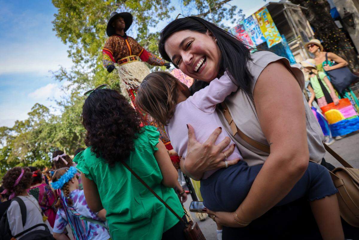 Andrea Isaac, right, dances with her daughter Valentina Isaac, 3, left, while Virgin Island Mocko Jumbies stilt dances warm-up before the parade.