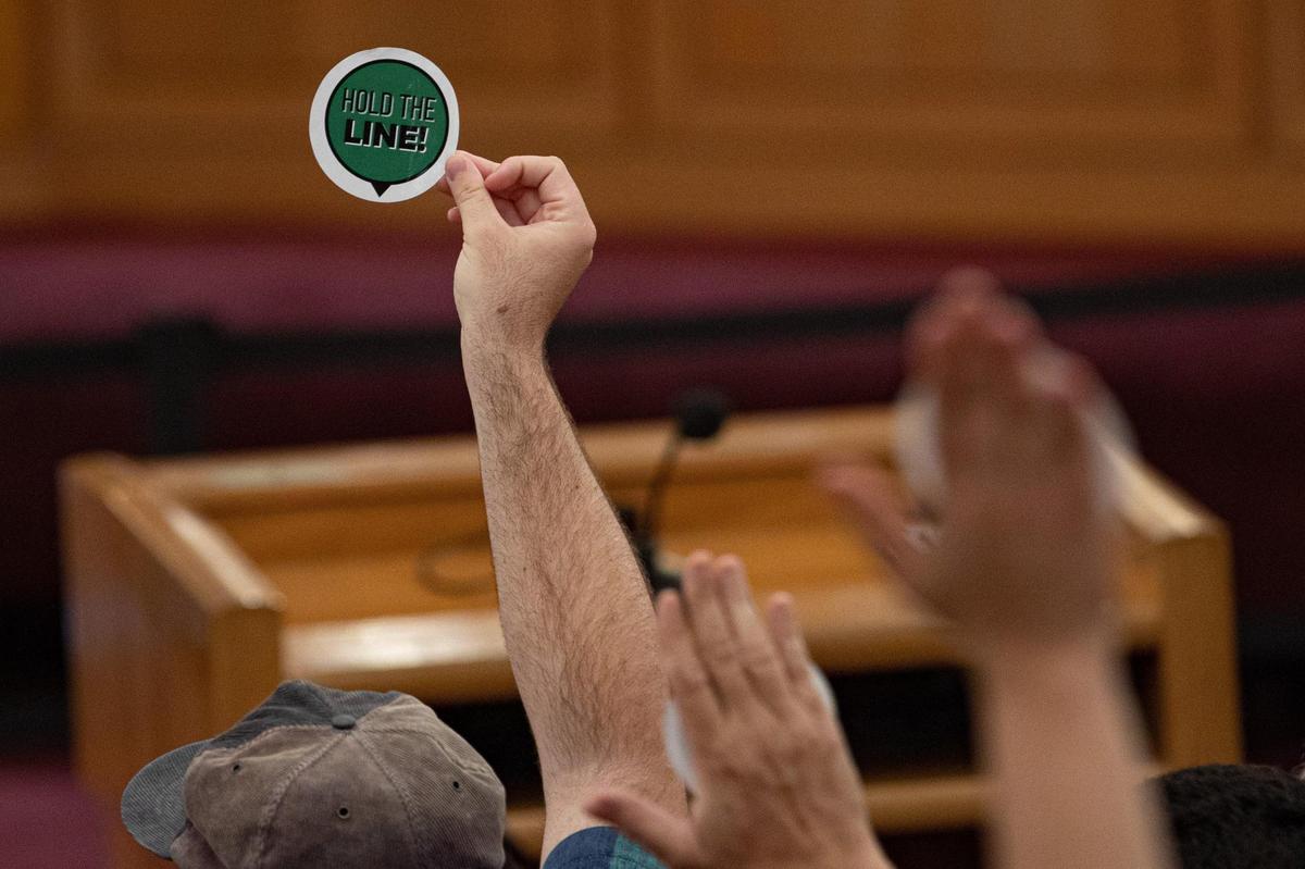 People raise “hold the line” stickers after Mayor Daniella Levine Cava’s veto is overriden during the Miami-Dade County Commissioners Meeting on Tuesday, November 15, 2022.
