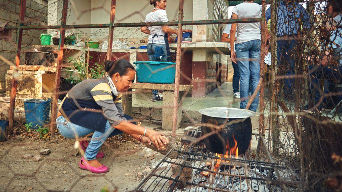 Women in Barquisimeto, Venezuela, cook food over wood fires for a feeding program for undernourished children.