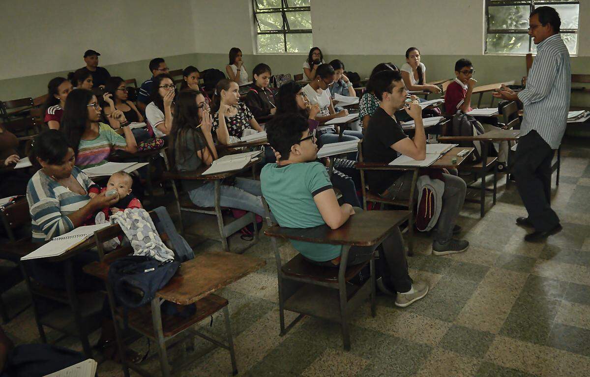 Moraxis sostiene a su bebé mientras asiste a la clase del Profesor Molina
