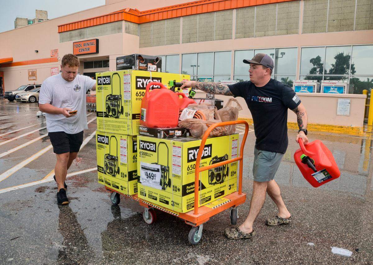 In this file photo from Sept. 28, 2022, Taylor Peat, at left, and Brady Bernstein, at right, of Sarasota, haul a load of generators and supplies for their families back home affected by Hurricane Ian as they leave the Home Depot store on Southwest Eighth Street in Miami's Little Havana neighborhood.