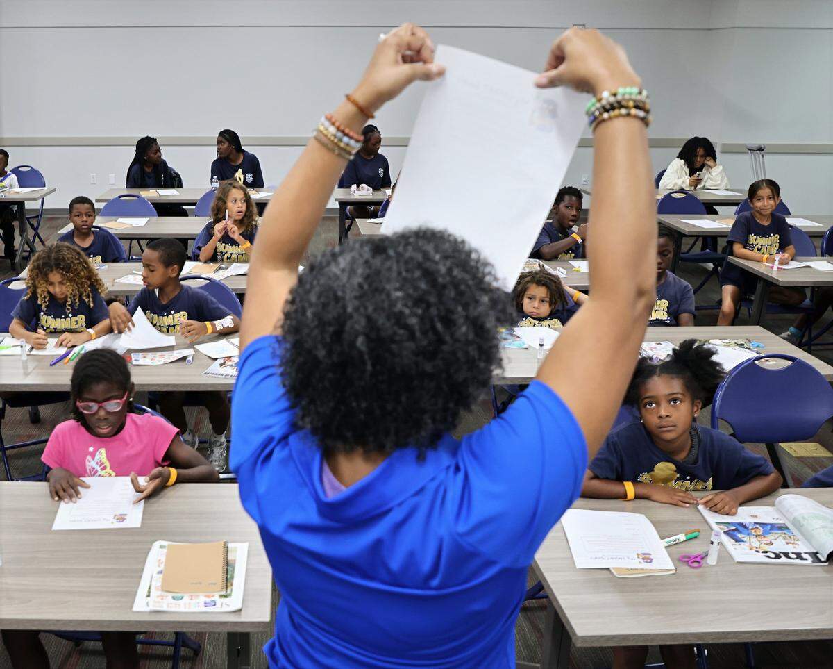 Workshop facilitator Kimberly Gray Roberts, center, holds up a paper encouraging attendees to list their goals for the upcoming academic school year during the Amplify Community Resources' 4th Annual Back-to-School Youth Readiness Summit on Thursday, July 31, 2025, at MDC Medical Campus in Miami, Florida.  