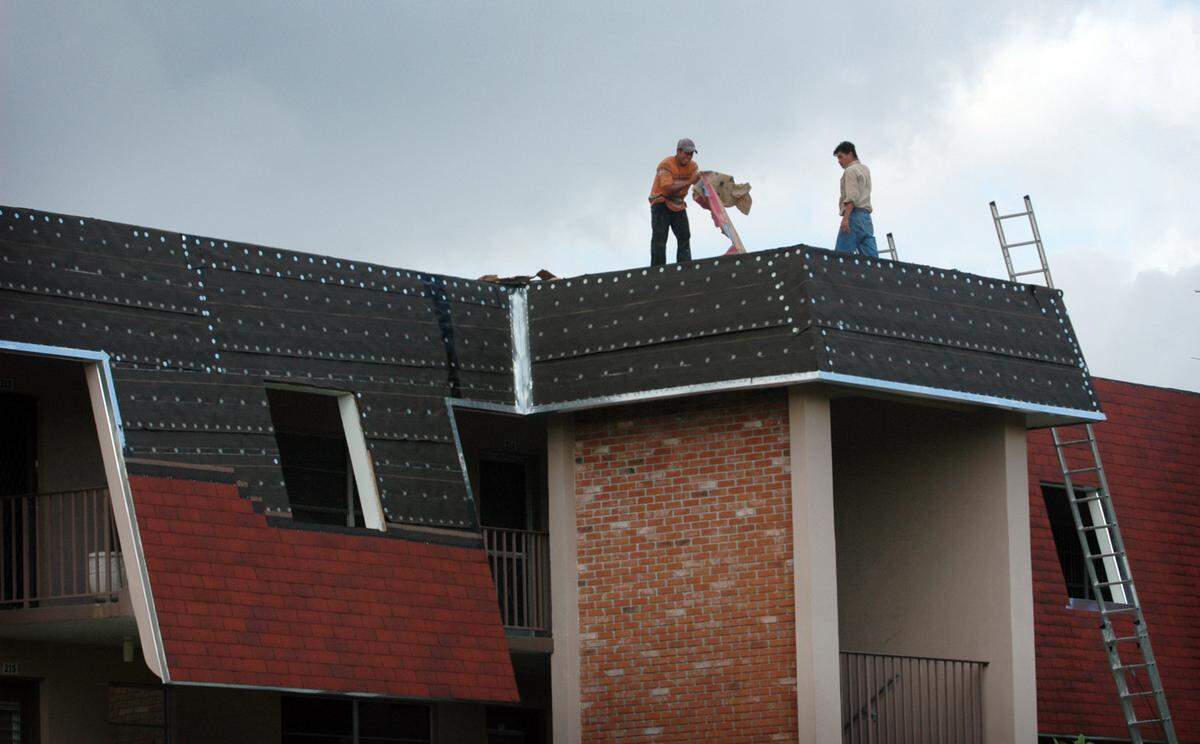 Roofers work on repairing roof damage at a Lauderdale Lakes condo.