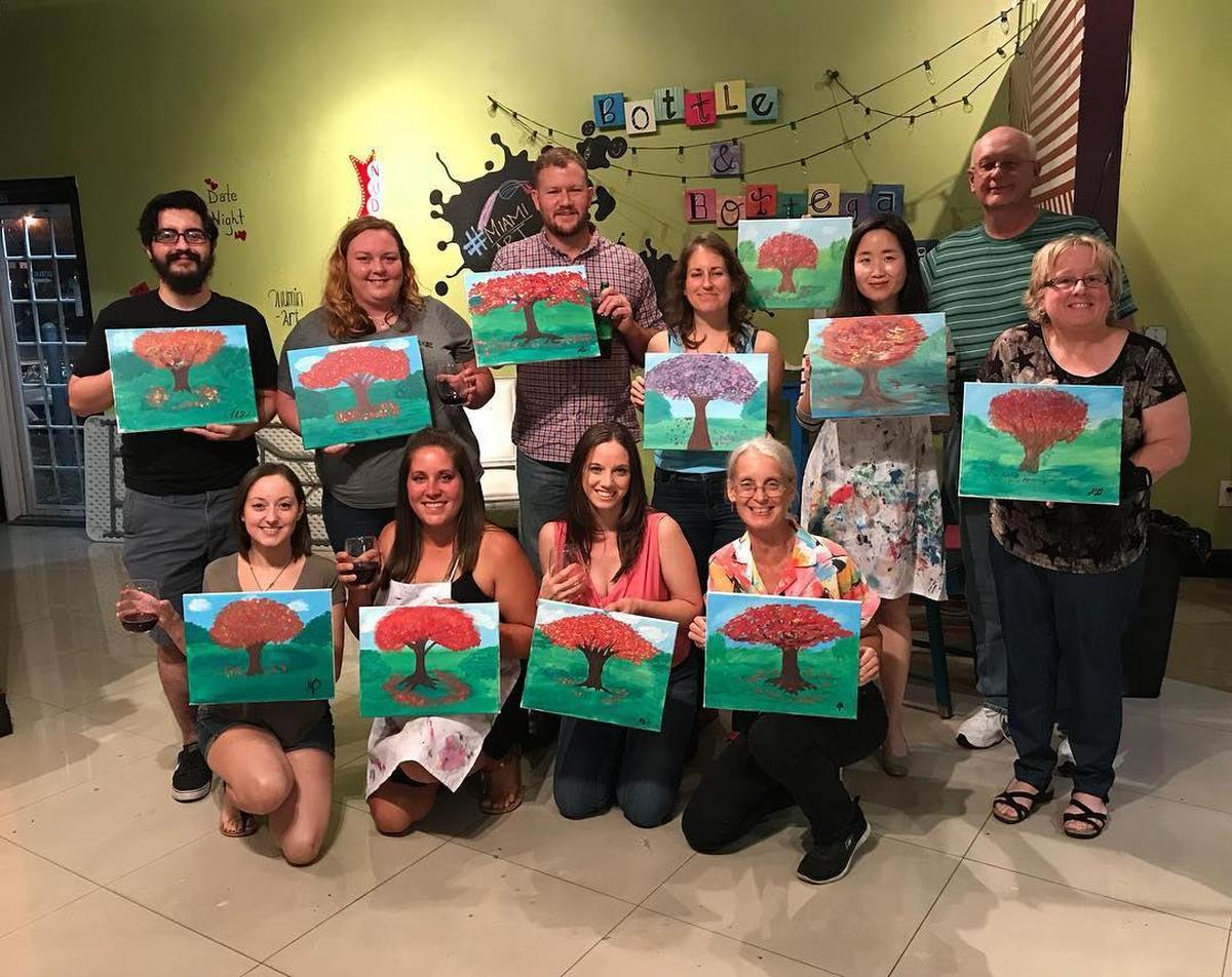Participants in the 2018 Painting Royal Poincianas cocktail party with a paintbrush show off their creations.