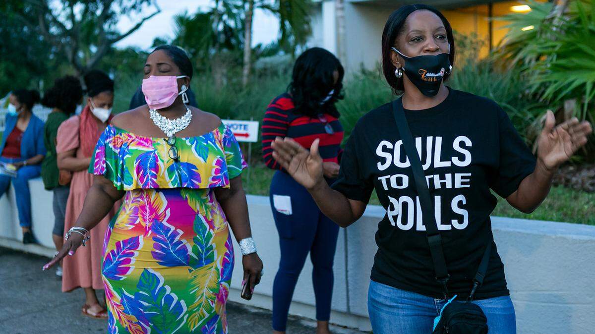 Pastor Stephanie E. Russell stands with voters lined up to cast ballots at the North Dade Regional Library in Miami Gardens.