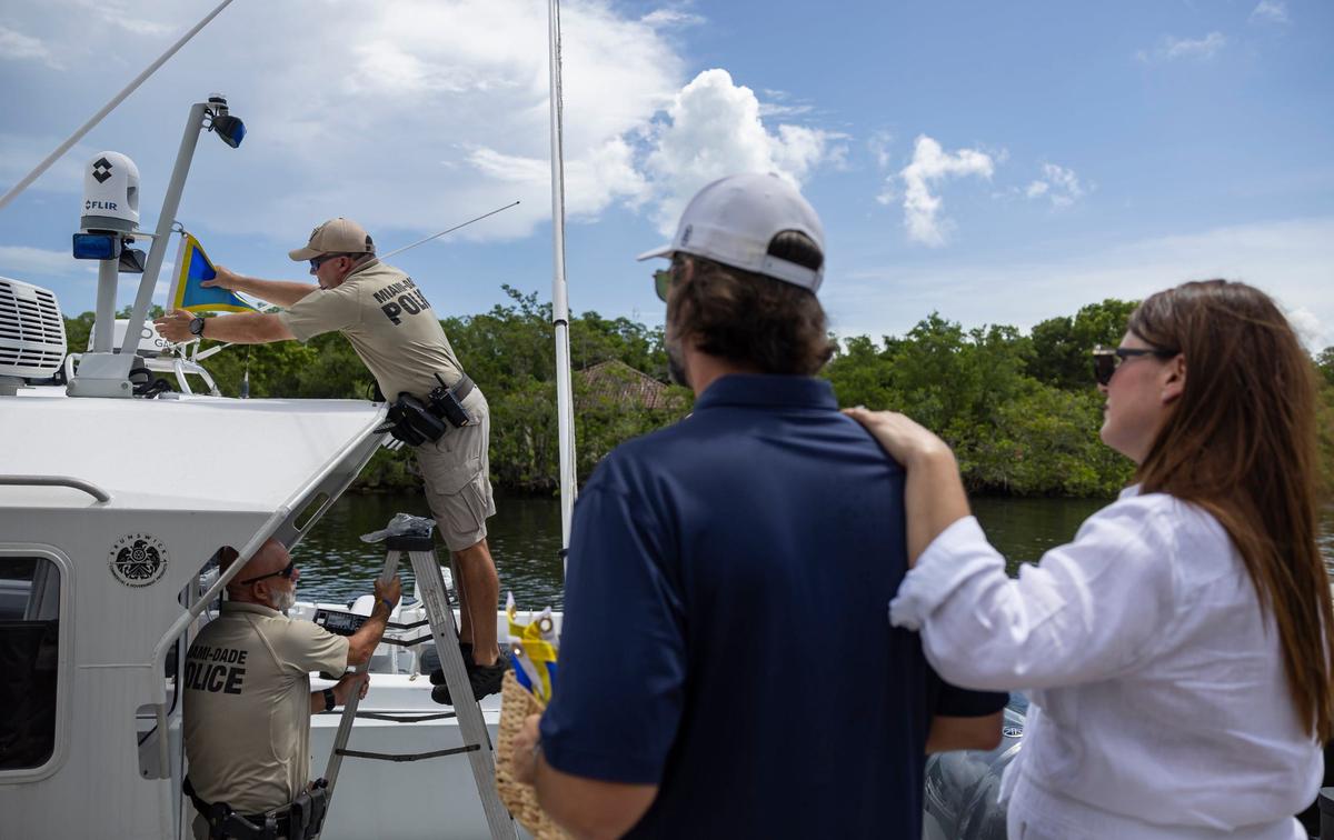 Melissa Fernandez and her husband, Andres Fernandez, watch as Miami-Dade Officers Thomas Kennedy, bottom-left, and Anthony Warren work to hang a Fly High, Bird flag on their boat at the Black Point Park and Marina on Friday, Aug. 30, 2024, in Homestead, Fla. The Fernandezes, who started the Lucy Fernandez Foundation after their daughter was killed in a boat crash two years ago, hope to raise awareness about boat safety with the flags that will hang on various Miami-Dade Police vessels.
