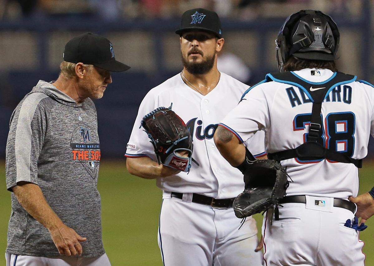 Miami Marlins pitcher Caleb Smith (31) talks with pitching coach Mel Stottlemyre Jr and catcher Jorge Alfaro (38) during the first inning of a Major League Baseball game against the Cincinnati Reds at Marlins Park in Miami on Tuesday, August 27, 2019.