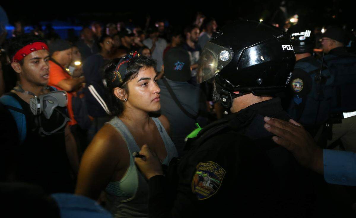 Una manifestante confronta a un policía que forma parte de un batallón que trata de despejar a un grupo que impide el acceso al Centro Cultural Yolanda Guerrero en Guaynabo, donde anteriormente el gobernador Ricardo Rosselló se reunió con un grupo de alcaldes de su partido el domingo 21 de julio de 2019.