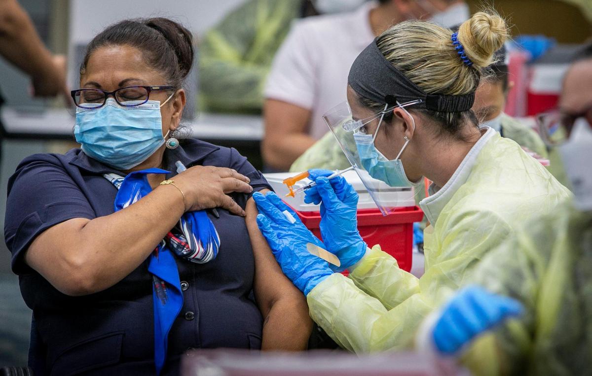 Shanta Seojatan, izquierda, que trabaja para American Airlines, recibe su vacuna Pfizer en el sitio de vacunación nuevo en el Concourse D en el auditorio del cuarto piso del Aeropuerto Internacional de Miami el 9 de mayo de 2021.