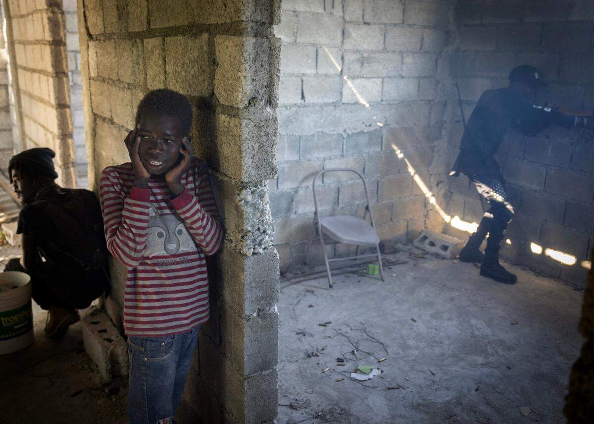 A child, screaming and covering his ears, stays close to the man on the left who was helping him during a recent gang firefight in Port-au-Prince. Hundreds of thousands of children have been displaced by the violence gripping the country.