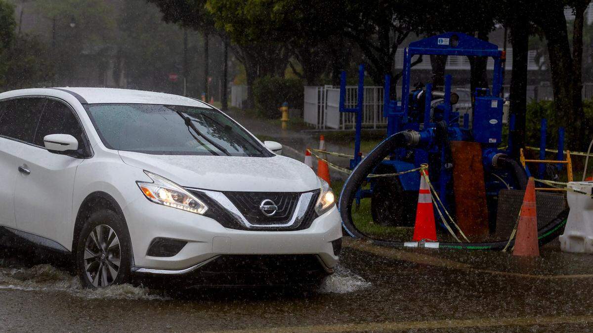 A temporary stormwater pump is seen turned off as a car crosses the flooded road caused by heavy rain on North Bay Rd and 179th Dr. in Sunny Isles Beach on Tuesday, June 11, 2024 in Florida.