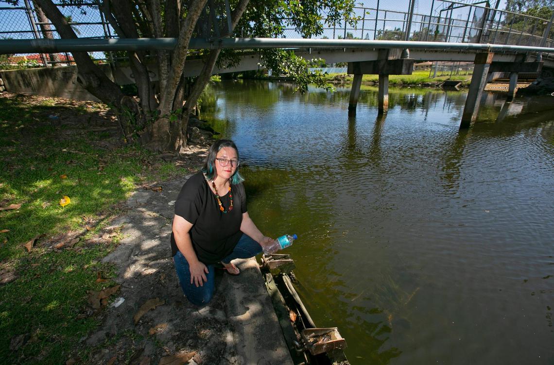 Kristen McLean, co-founder of the Little River Conservancy, picks up a discarded water bottle near the river’s edge close to where a shopping cart lies submerged in the water near the pedestrian bridge in El Portal.