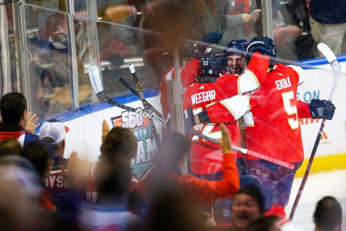 Florida Panthers defender MacKenzie Weegar (52) is embraced by his teammates after scoring on Columbus Blue Jackets goalie Elvis Merzlikins (90) during the first period of an NHL game goalie FLA Live Arena in Sunrise, Florida, on Saturday, January 15, 2022.