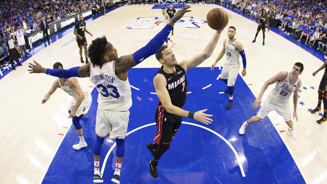 In this photo taken with a fisheye lens, Miami Heat's Goran Dragic, center right, of Slovenia, shoots with Philadelphia 76ers' Robert Covington, left, defending during the second half in Game 1 of a first-round NBA basketball playoff series, Saturday, April 14, 2018, in Philadelphia.