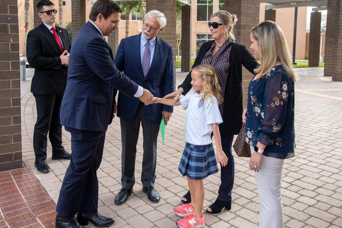 Governor Ron DeSantis is greeted by 9-year-old Peyton Hoover Rood,granddaughter of Florida Prepaid Board Chairman John D. Rood Monday, Jan. 13 shortly before he announced the price cut to Florida Prepaid College tuition plans.
