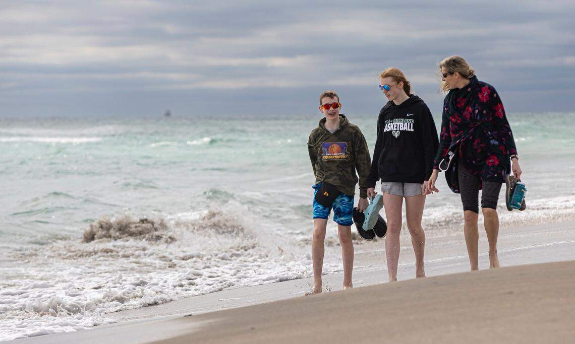 Cole Shaffer, Rebekah Shaffer and their mom, Stacey Shaffer, make their way down the beach as they visit the Hollywood Beach Broadwalk on Monday, Feb. 19, 2024, in Hollywood, Fla. After strong winds and rain showered parts of South Florida on Sunday, the temperature dipped into the mid-60s Monday morning.
