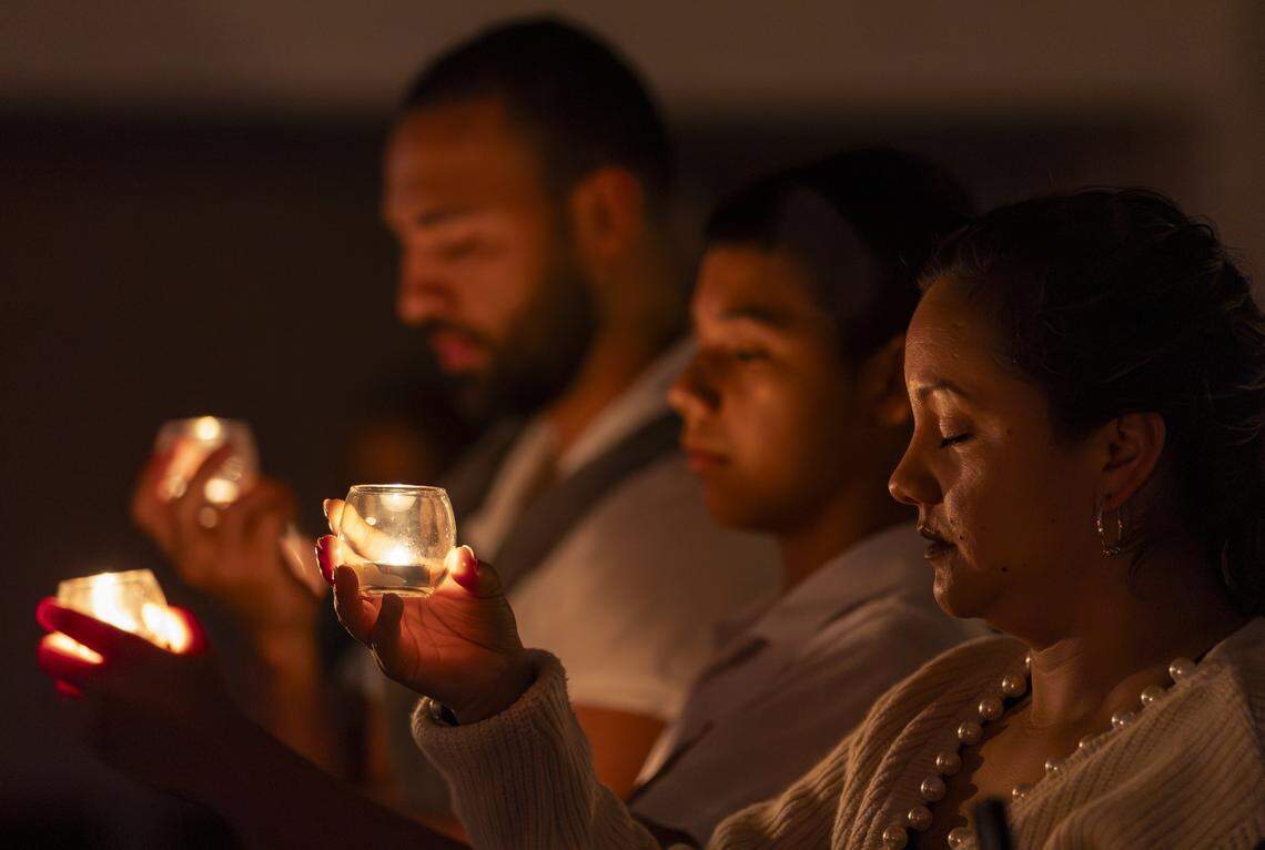From left to right: Leandro Giraldo, Juan Pablo Susa and Mayerly Susa hold candles and pray during a vigil at Christ Lutheran Church on Saturday, Aug. 9, 2025, in Oakland Park, Fla. The vigil brought together immigrant families and others supporting loved ones in migrant detention centers, such as Alligator Alcatraz, across the state and country.