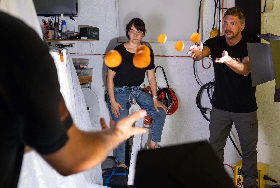 Ania Moussawel (left) watches as Luis Corchon (right) and Aguila throw oranges to each other right in front of the backdrop to see if adding depth to the video would make it look better.
