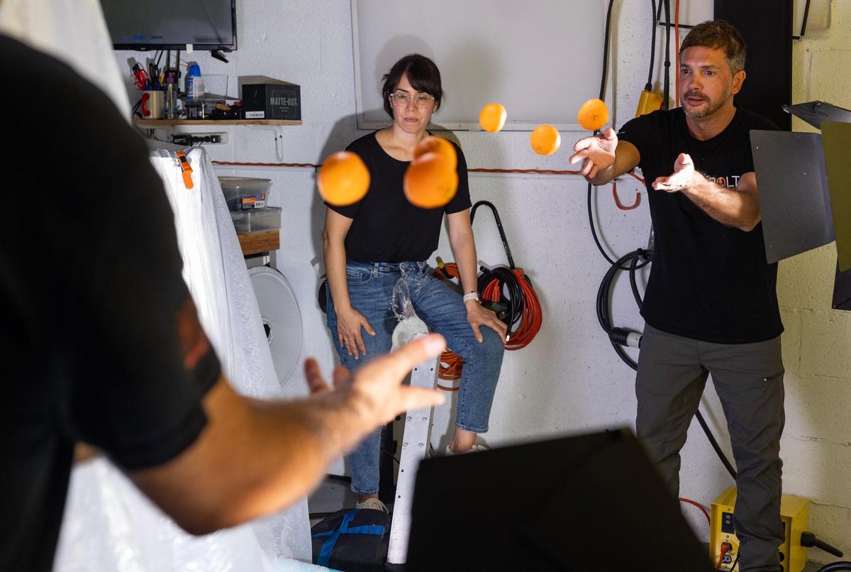 Ania Moussawel (left) watches as Luis Corchon (right) and Aguila throw oranges to each other right in front of the backdrop to see if adding depth to the video would make it look better.