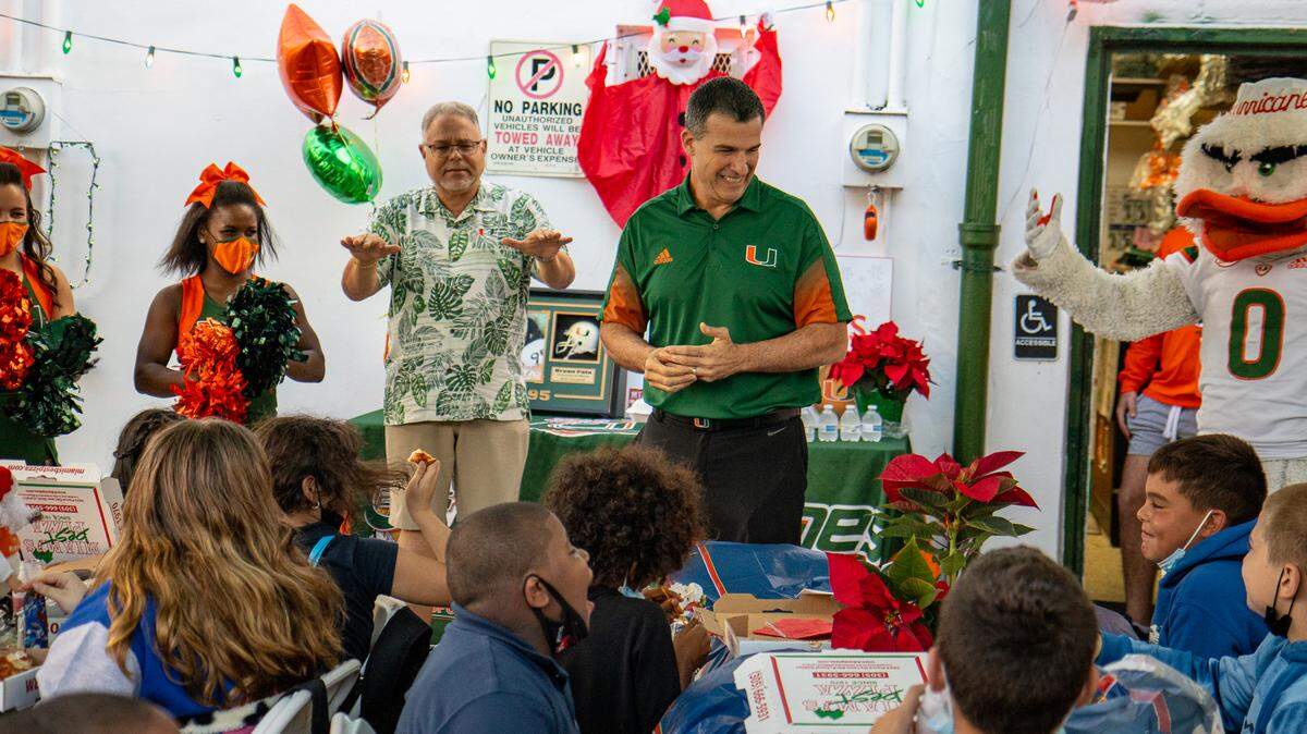 Miami Hurricanes coach Mario Cristobal visits with children who attended the allCanes Shopping Spree for Kids that benefited the Bryan Pata Foundation. Also in the photo is allCanes general manager Harry Rothwell.