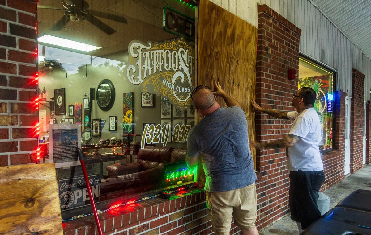 David Parker (left) and Jesse Cuen put up plywood boards to the windows and doors at the High Class Ink Studios in Palm Bay, in North East Florida in preparation for Hurricane Milton on, Tuesday October 08, 2024.
